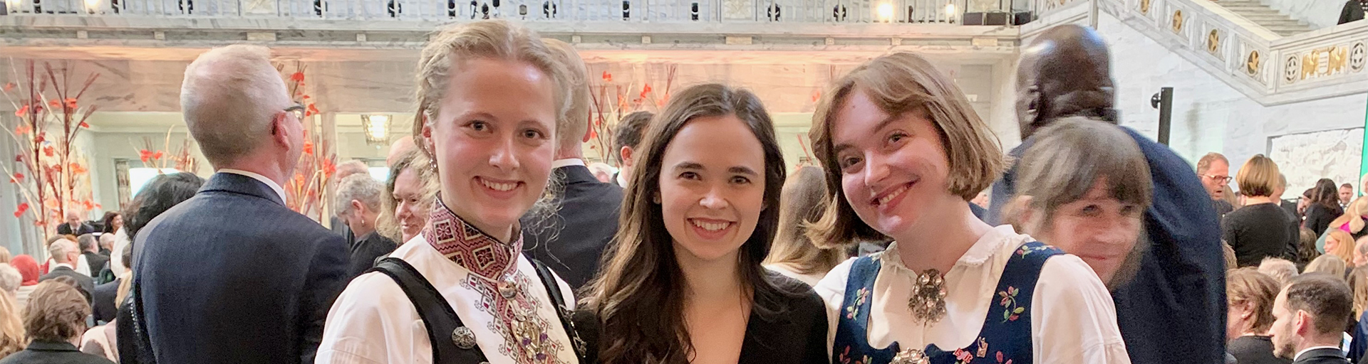 Three students smiling in front of a crowd