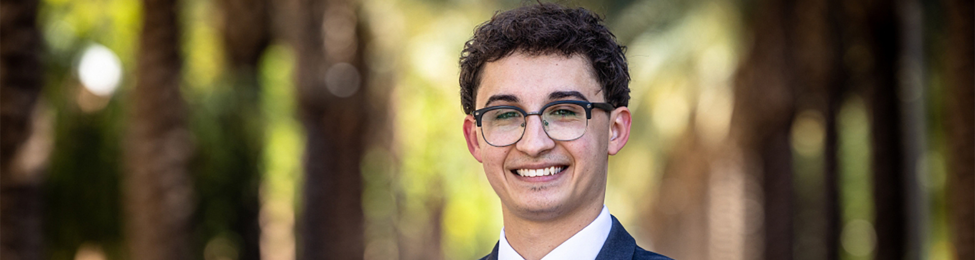 Student smiling exterior with trees in background